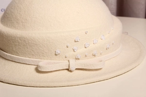 Close-up of wool cloche hat featuring decorative bow with pearl and floral details