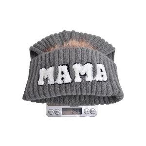 Dettaglio del peso di un berretto in maglia MAMA con pompon in ecopelliccia su bilancia