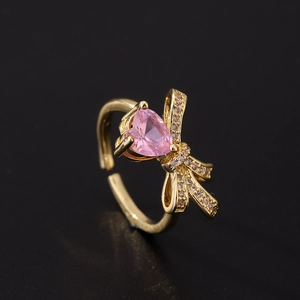 Gros plan d'une bague cœur rose avec nœud élégant et anneau doré ajustable pour femmes