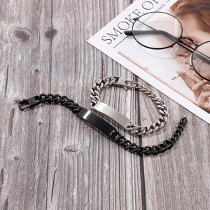 Detail view of black and silver stainless steel Cuban bracelets on a wooden surface