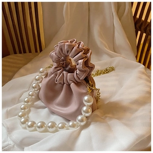 Detail of pink pleated PU leather girl handbag with large pearl and gold metal chains