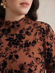 Détail du haut en tulle marron avec fleurs floquées noires et boucles d'oreilles dorées