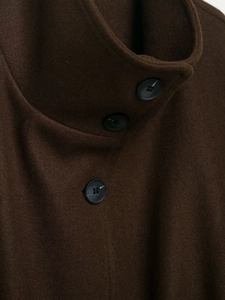 Detail of dark brown wool coat collar with classic black three-hole button closure
