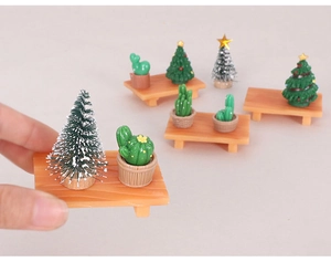 Detailed close-up of mini resin Christmas tree and cactus models on wooden stands