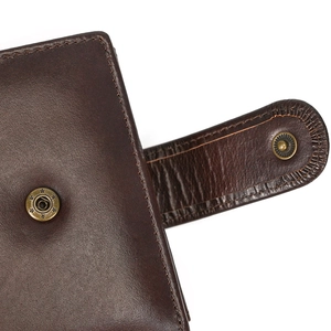 Detail of dark brown leather wallet with vintage star button and stitching