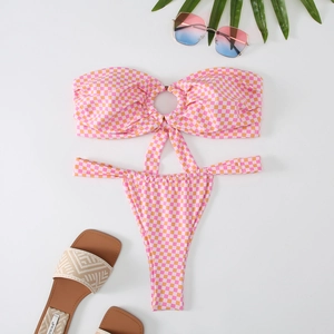 Flat lay of pink and orange checkered bikini set with center ring and vacation accessories