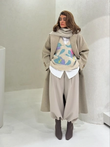 Detail of a chic layered spring outfit with beige wool coat and knit sweater