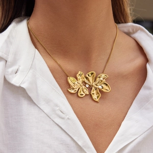 Elegant 18K gold plated stainless steel floral necklace with central crystal on white shirt