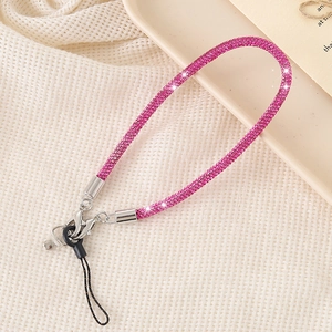 Sparkling magenta rhinestone phone wrist strap with metal clips on beige background