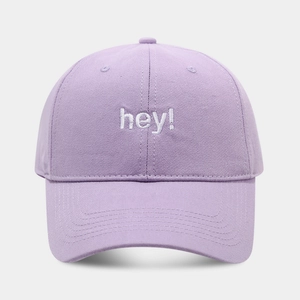 Detail of lavender baseball cap with white 'hey!' embroidery on soft cotton twill fabric
