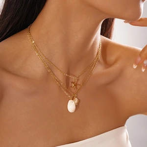 Close-up of a 3-layer gold starfish and shell pendant necklace on woman's neck