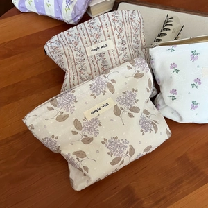 Detailaufnahme kleiner Stoff-Kosmetiktaschen mit Blumenmuster auf einem Holztisch