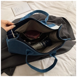 Detail of spacious denim tote bag interior showing side pocket and daily essentials