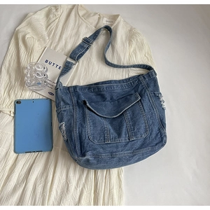 Détail du sac à bandoulière en denim bleu avec poche à rabat et bords à franges