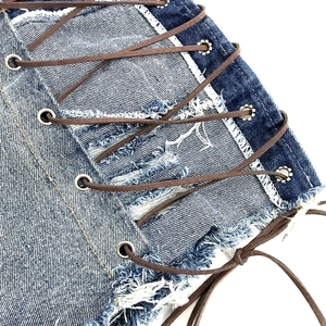 Dettaglio pantaloncini di denim blu con lacci marroni incrociati e occhielli in metallo