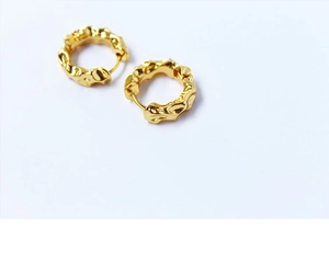 Détail macro de boucles d'oreilles en laiton plaqué or 18k avec texture lave irrégulière