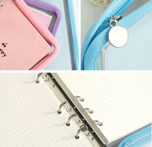Detail of metal ring binder, grid paper, and smooth zipper on colorful cherry notebook