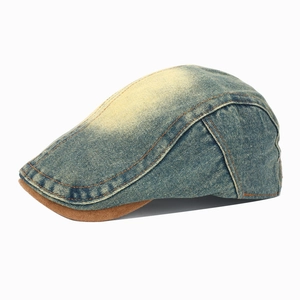Detail of washed denim beret with orange contrast stitching and brown suede brim