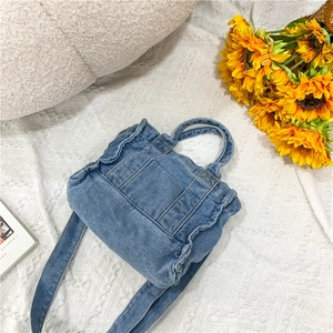 Blue denim crossbody bag with ruffle trim on lace background with sunflowers