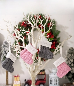 Detail of pink and grey knitted mini Christmas stockings with hanging ropes and cable texture