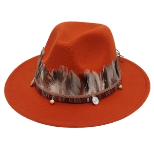 Detail eines ethnischen orangefarbenen Filzhutes mit Federn und Boho-Verzierungen