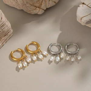 Détail de boucles d'oreilles créoles dorées et argentées avec pendentifs en perles