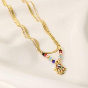 Detail of gold double-layered necklace with Hamsa Hand pendant and colorful zircons