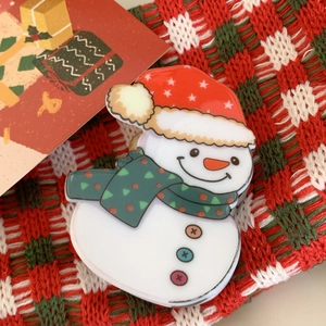 Detailed close-up of a white snowman Christmas hair claw with red hat and green scarf