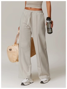 Detail of high-waisted loose joggers with front seam and drawstring waist in light grey