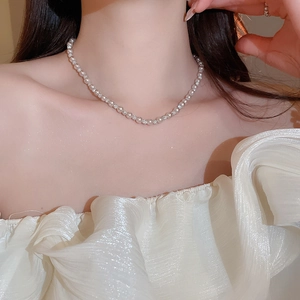 Close-up of elegant pearl and rhinestone beaded necklace set on woman neck