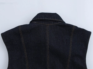 Detailed close-up of dark blue denim vest showing premium orange contrast stitching