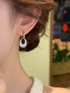 Close-up of sparkling zircon teardrop earrings in silver on a model ear