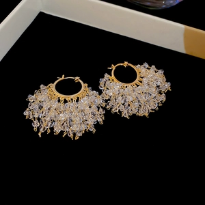 Close-up of 18k gold plated hoop earrings with dangling clear crystal tassel drops