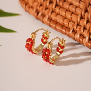 Detail of gold wheat ear U-shaped earrings with red marquise-cut stones on a leaf design