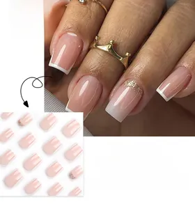 Detail of French style press-on nails with white tips, pink gradient and gold glitter