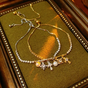 Close-up of gold and silver pearl bracelets with zircon cross charms on green velvet