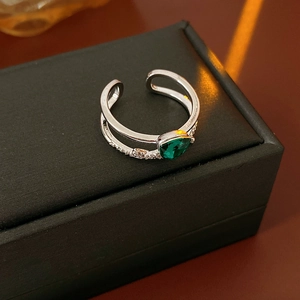 Détail de bague ouverte avec zircon vert en goutte et monture argentée scintillante