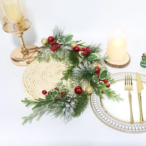 Christmas pine needle garland with red berries and gold ornaments on a holiday dinner table