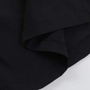 Détail macro du pantalon large noir montrant les coutures doubles et la finition soignée