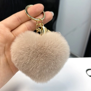 Close-up of a soft heart-shaped plush keychain in light brown with a gold metal ring