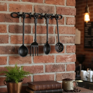 Vintage-Wanddeko-Set aus schwarzem Gusseisen mit vier Küchenwerkzeugen an Backsteinwand