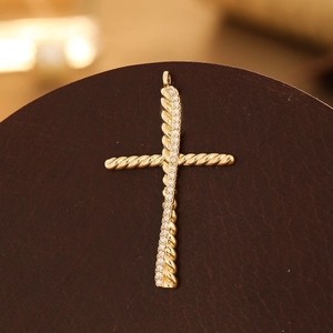 Detailed view of a gold cross pendant with twisted rope texture and micro-pave zircons