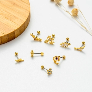 Detailed view of assorted gold ear studs with zircon crosses and flower motifs