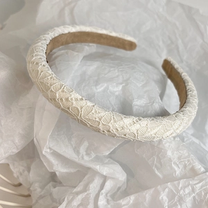 Detailed view of white floral lace texture and sponge padding on a padded headband