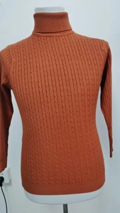 Dettaglio del maglione a collo alto arancione con trama in maglia a trecce complessa