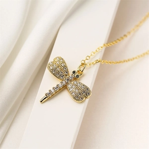 Macro close-up of golden dragonfly pendant with sparkling cubic zirconia on chain