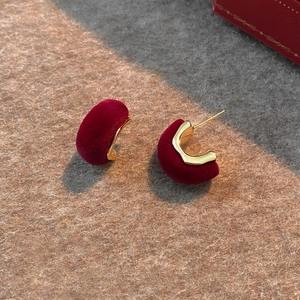 Close-up of vintage burgundy velvet C-shaped earrings with gold metal base on felt