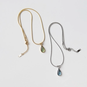 Detail of teardrop pendant necklaces with snake chains and engraved metal tags