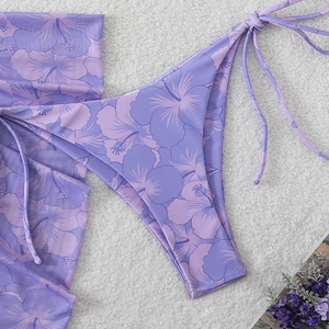 Detailed view of purple floral print bikini with tie-side briefs on soft white texture