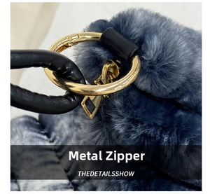 Close-up of golden hardware zipper and faux fur texture on the gray-blue handbag